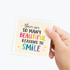 May include: A colorful card with the text "there are so many beautiful reasons to smile" with yellow stars on a cream background.