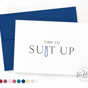 May include: White card with blue envelope. The card has the text "TIME TO SUIT UP" with a blue tie icon in the middle of the word "SUIT". The bottom right corner of the card has the text "KREATE PAPER CO. the Wedding collection PONTE VEDRA, FL."