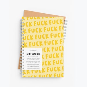 May include: A spiral-bound notebook with a yellow cover featuring the word "FUCK" in a repeating pattern. The notebook includes a small white label with the word "NOTEBOOK" and text describing its features. The notebook is on top of a brown paper.