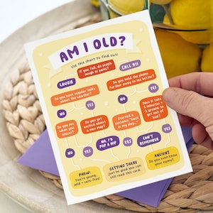 May include: A humorous greeting card with the text "AM I OLD?" in a playful font. The card features a flowchart with questions like "Do you have regular talks about the weather?" and "Do you get excited about a new map?"