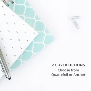 K&ouml;nnte beinhalten: Ein wei&szlig;es Notizbuch mit einem hellblauen, gemusterten Einband und einem silbernen Stift. Der Einband hat ein sich wiederholendes Kleeblatt-Muster. Der Text "2 COVER OPTIONS Choose from Quatrefoil or Anchor" ist auf wei&szlig;em Hintergrund sichtbar.