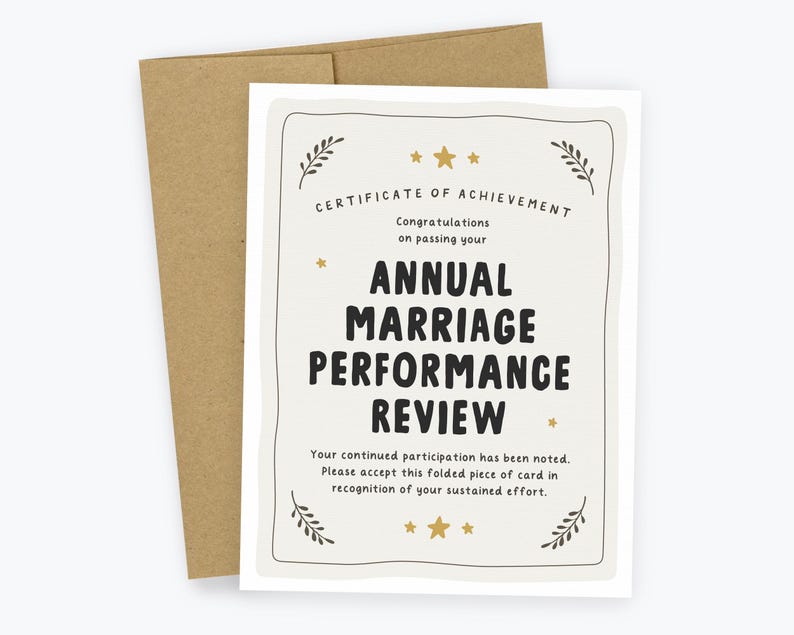 May include: A white greeting card with a brown envelope featuring the text Certificate of Achievement, Congratulations on passing your Annual Marriage Performance Review, and Your continued participation has been noted. Please accept this folded piece of card in recognition of your sustained effort, decorated with gold stars and leaf motifs.