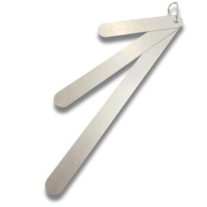 May include: A silver-colored, hinged metal ruler with rounded ends and a small loop at the top. The ruler is folded open, displaying three sections. The background is plain white.