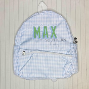 May include: A blue and white gingham backpack with a green and white embroidered name "MAX" and the text "SOUTHERN heritage" on the front.