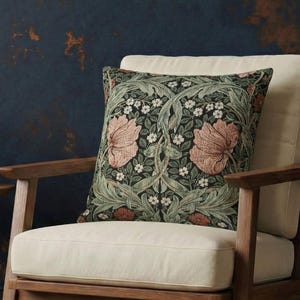 May include: A wooden armchair with a cream-colored cushion and a decorative pillow featuring a floral pattern in shades of green, pink, and white. A small wooden side table holds three teal vases with copper-colored bases. The room has a dark blue wall.