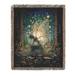 May include: A woven throw blanket featuring a fairy in a forest scene. The fairy has large, detailed wings and is surrounded by mushrooms and glowing lights. The blanket has a dark background with a fringed edge.
