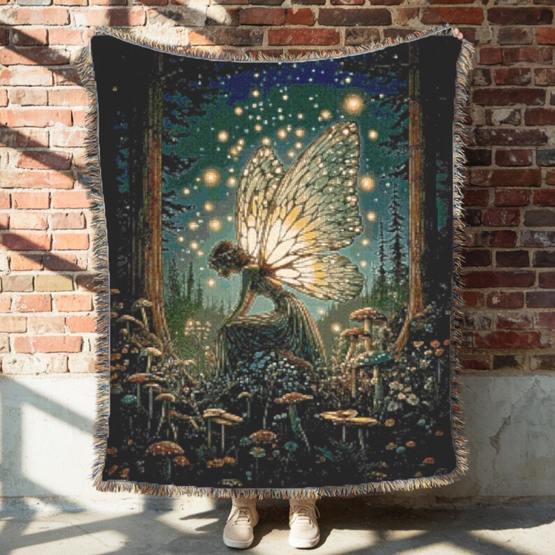 May include: A woven throw blanket featuring a fairy in a forest scene with mushrooms and glowing lights. The fairy has large, detailed wings. The color palette includes greens, browns, and blues, creating a whimsical and enchanting design.