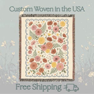 May include: Woven floral throw blanket featuring a cream background with a pattern of pink, yellow, and rust-colored flowers and green ferns. The blanket has a scalloped border and the text "Custom Woven in the USA".