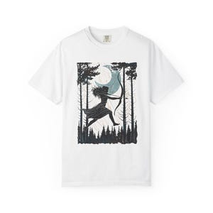 May include: White t-shirt featuring a black and teal graphic of a person with a bow and arrow, running through a forest under a crescent moon. The design includes silhouettes of trees and a forest floor.