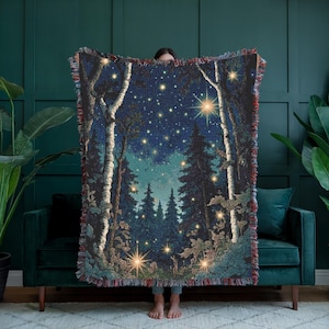 May include: A woven throw blanket featuring a dark blue night sky filled with bright stars and glowing fireflies. The scene depicts a dense forest with tall birch trees in the foreground and evergreen trees in the background, finished with a fringed edge.
