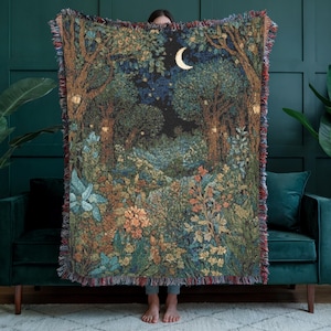 Puede incluir: Una manta de tapiz tejida con una escena de bosque nocturno, con una luna creciente. El diseño detallado presenta árboles, follaje y un sendero. Los bordes están flecados con hilos rojos, azules y marrones. Mide aproximadamente 150 cm x 200 cm.
