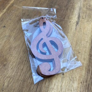 May include: Two brown wooden treble clef earrings packaged in a clear plastic bag.