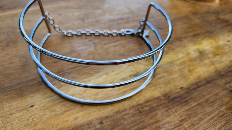 May include: A silver metal choker necklace with a double-layered design and a chain closure.