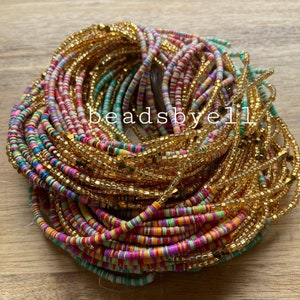 Könnte beinhalten: Ein farbenfroher Perlen-Taillenschmuck-Set mit einer goldenen Kette. Die Perlen sind in verschiedenen Farben, darunter Rot, Pink, Grün, Blau und Weiß. Die goldene Kette besteht aus kleinen, runden Perlen.