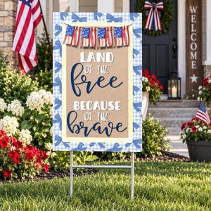 May include: A rectangular yard sign featuring a blue and white gingham border with blue bow accents. The center displays a tan background with a hanging flag bunting and the text LAND OF THE FREE BECAUSE OF THE BRAVE in blue and white lettering.