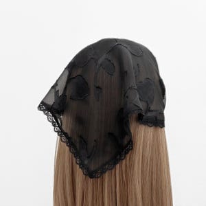 May include: Black lace head covering with a floral pattern. The lace is delicate and has a scalloped edge.