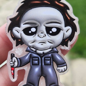 Può includere: Una piccola figura di stile cartone animato di Michael Myers del franchise di Halloween. Indossa una tuta blu e una maschera bianca. Tiene un coltello insanguinato nella mano destra.