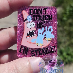 Puede incluir: Fondo de purpurina rosa con una imagen de dibujos animados de Bob Esponja con guantes azules y un estetoscopio. El texto dice "¡No me toques! ¡Estoy estéril!"