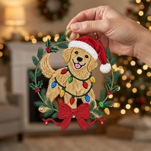 May include: A circular embroidered ornament featuring a golden retriever puppy wearing a red and white Santa hat. The puppy is wrapped in a string of colorful Christmas lights, framed by green pine needles, holly berries, and a large red bow.