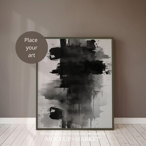 Puede incluir: Una pintura abstracta en blanco y negro en un marco gris oscuro, colgada en una pared marrón. La pintura es un diseño abstracto grande con pinceladas negras y grises. El marco es simple y moderno.