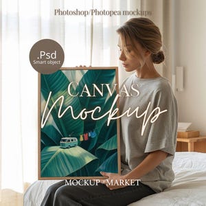 May include: A framed canvas mockup featuring a tropical leaf design with a small blue van and colorful clothesline. The words "CANVAS Mockup" are displayed in a cursive font. The image is held by a person wearing a gray t-shirt.