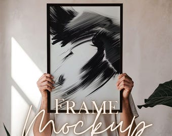 May include: A person holds a black framed print with a black and white abstract design. The text "FRAME MOCKUP" is written below the frame.
