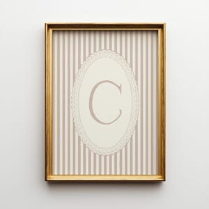 Heirloom-inspired monogram nursery wall art featuring the initial 'C' within a lace frame against classic pink and white stripes.  A natural fit for interiors inspired by the feminine, refined aesthetic of spaces thoughtfully curated by Anthropologie and Studio McGee.
