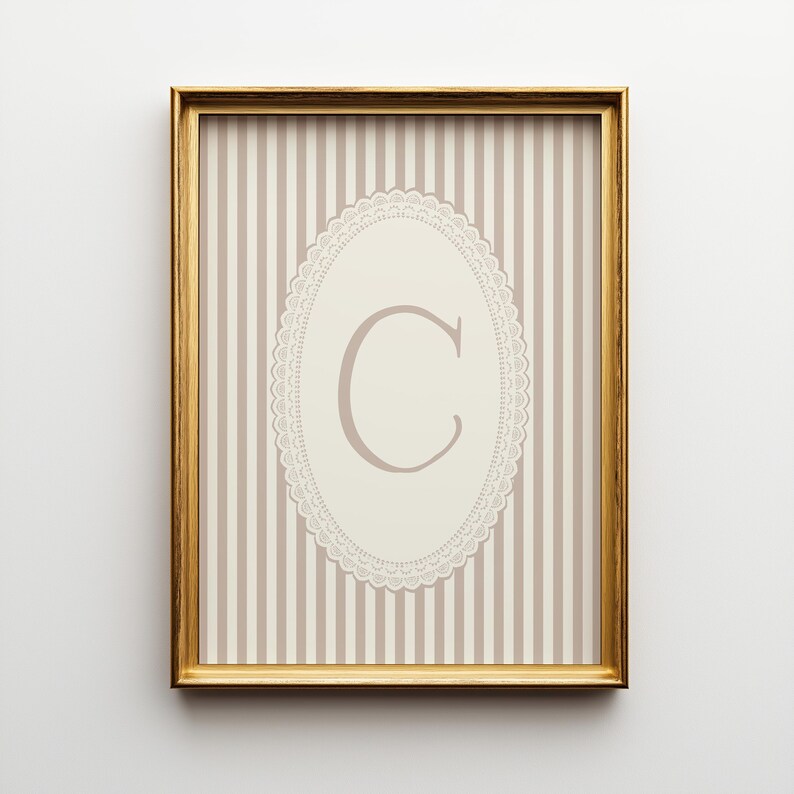 Heirloom-inspired monogram nursery wall art featuring the initial 'C' within a lace frame against classic pink and white stripes.  A natural fit for interiors inspired by the feminine, refined aesthetic of spaces thoughtfully curated by Anthropologie and Studio McGee.