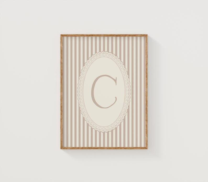 Heirloom-inspired monogram nursery wall art featuring the initial 'C' within a lace frame against classic pink and white stripes.  A natural fit for interiors inspired by the feminine, refined aesthetic of spaces thoughtfully curated by Anthropologie and Studio McGee.