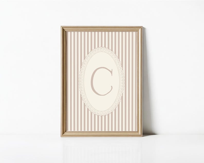 Heirloom-inspired monogram nursery wall art featuring the initial 'C' within a lace frame against classic pink and white stripes.  A natural fit for interiors inspired by the feminine, refined aesthetic of spaces thoughtfully curated by Anthropologie and Studio McGee.