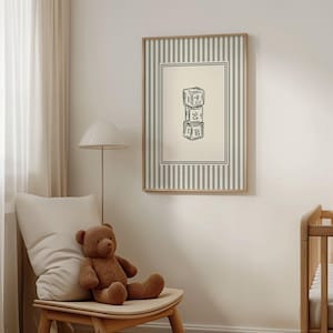 Peut inclure: Une affiche encadrée représentant trois blocs de jouets empilés, chacun portant un numéro de un à trois. L'œuvre est dans un cadre en bois avec un fond à rayures vertes et blanches. Un ours en peluche est assis sur une chaise en bois.