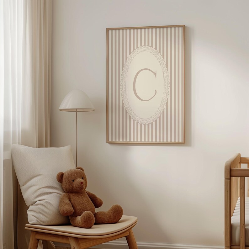Heirloom-inspired monogram nursery wall art featuring the initial 'C' within a lace frame against classic pink and white stripes.  A natural fit for interiors inspired by the feminine, refined aesthetic of spaces thoughtfully curated by Anthropologie and Studio McGee.