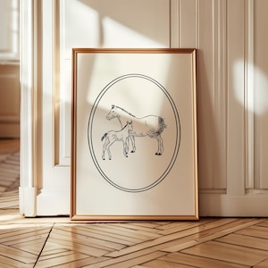 Puede incluir: Una impresión enmarcada con una ilustración en blanco y negro de una yegua y un potro dentro de un óvalo. La obra de arte está sobre un fondo crema y enmarcada en un marco dorado. La impresión se muestra contra una pared blanca y un suelo de madera.