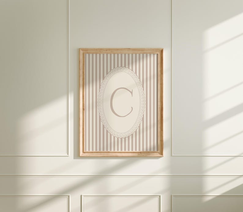 Heirloom-inspired monogram nursery wall art featuring the initial 'C' within a lace frame against classic pink and white stripes.  A natural fit for interiors inspired by the feminine, refined aesthetic of spaces thoughtfully curated by Anthropologie and Studio McGee.