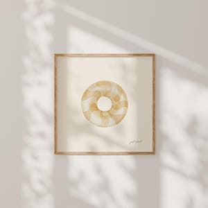 Puede incluir: Una impresión enmarcada con una ilustración en acuarela de un donut. El donut es de color marrón claro con un patrón de remolino blanco. La impresión está en un marco de madera y tiene las palabras "just float" en la esquina inferior derecha.
