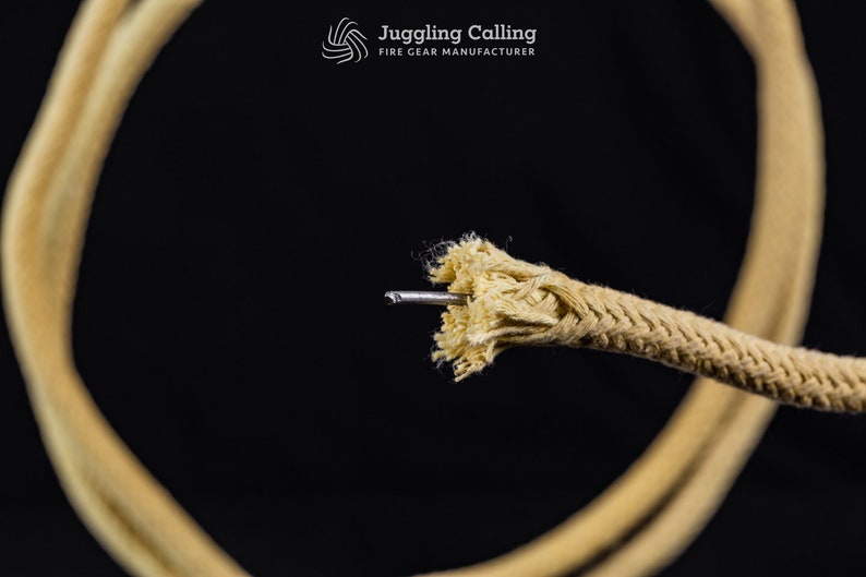 May include: Close-up of a beige cotton rope with a metal wire core. The rope is frayed at the end where the wire is visible. The rope is coiled in a circle in the background.
