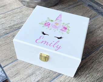 Può includere: Scatola di legno bianca con un design di unicorno e fiori rosa. La scatola ha una chiusura dorata e il nome "Emily" è stampato sul davanti.