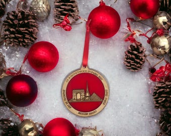 May include: A red and gold Christmas ornament featuring the text "OUR HONEYMOON IN PARIS 2023" and illustrations of the Eiffel Tower, Arc de Triomphe, and Louvre Museum. The ornament is surrounded by red baubles, pine cones, and decorative accents.