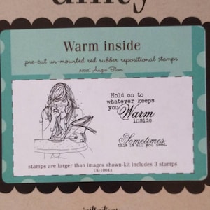 May include: A teal and white stamp set with the words "Warm inside" and a drawing of a woman drinking from a mug. The set includes pre-cut, un-mounted red rubber repositional stamps. The text "Hold on to whatever keeps you warm inside" is also included.