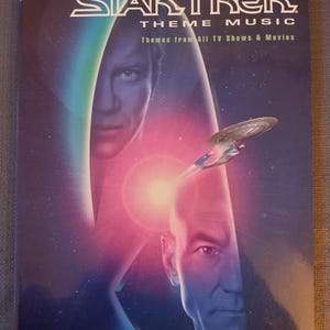 May include: A Star Trek theme music book with a cover featuring images of characters and the Star Trek starship. The book is labeled "Complete Star Trek Theme Music" and includes the Hal Leonard logo. The cover has a blue, purple, and green color scheme.