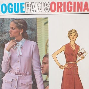 May include: A Vogue Paris Original sewing pattern envelope featuring a photograph of a person wearing a light pink belted jacket with a white collared shirt and a fashion illustration of a sleeveless, button-front dress with a belt and pockets.
