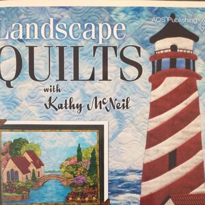 May include: A book cover titled Landscape Quilts with Kathy McNeil, featuring a large red and white striped lighthouse against a blue sky and sea background, with an inset image of a house, stone bridge, and garden scene at the bottom left.