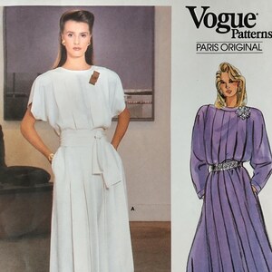 May include: Vogue Patterns Paris Original sewing pattern featuring two dress designs. The first design is a white jumpsuit with a sash and the second design is a purple dress with a gathered skirt.