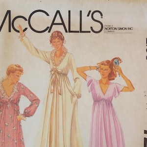 May include: A vintage McCall's sewing pattern envelope featuring illustrations of three long dresses. One dress is pink with a floral print, one is solid cream, and one is solid light purple. All dresses have empire waists and V-necklines.