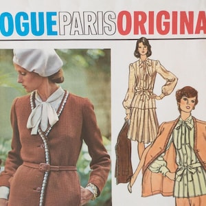 May include: A Vogue Paris Original sewing pattern envelope featuring a photograph of a person wearing a brown textured jacket with a white beret and a blouse with a bow tie, alongside illustrations of a two-piece outfit with a jacket and skirt.