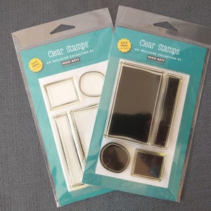 May include: Two packages of clear stamps. Each package has a teal backing with the words "Clear Stamps" and "An Exclusive Collection by Hero Arts". The stamps are various shapes, including rectangles and ovals.