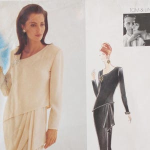 May include: A sewing pattern envelope featuring Tom & Linda Platt designs. The cover displays a cream-colored long-sleeve dress with an asymmetrical neckline and a brooch, alongside a black-and-white illustration of a similar long-sleeve dress.