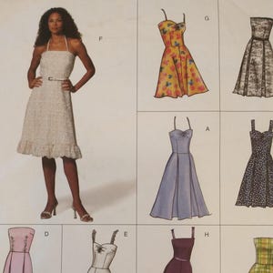 May include: A woman in a white halter dress with a belt stands next to illustrations of various dresses. The illustrations include a yellow floral dress, a black lace dress, a blue dress, and a black polka dot dress.