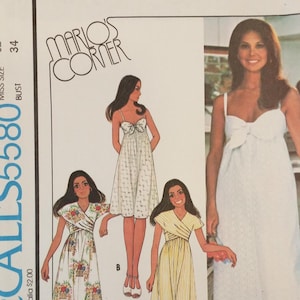 May include: A McCall's 5580 sewing pattern envelope titled Mario's Corner featuring illustrations and a photograph of three different dress styles. The designs include a white dress with a front bow, a floral print wrap dress, and a yellow striped wrap dress.