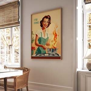 May include: A vintage-style poster featuring a woman in a green apron standing in a kitchen with a pot on the stove that is on fire. The text on the poster reads "I'm Fine."